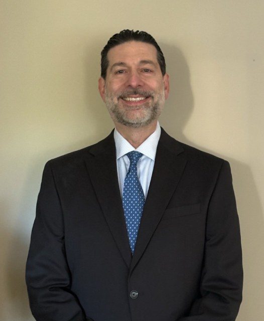 Man in suit smiling against beige background